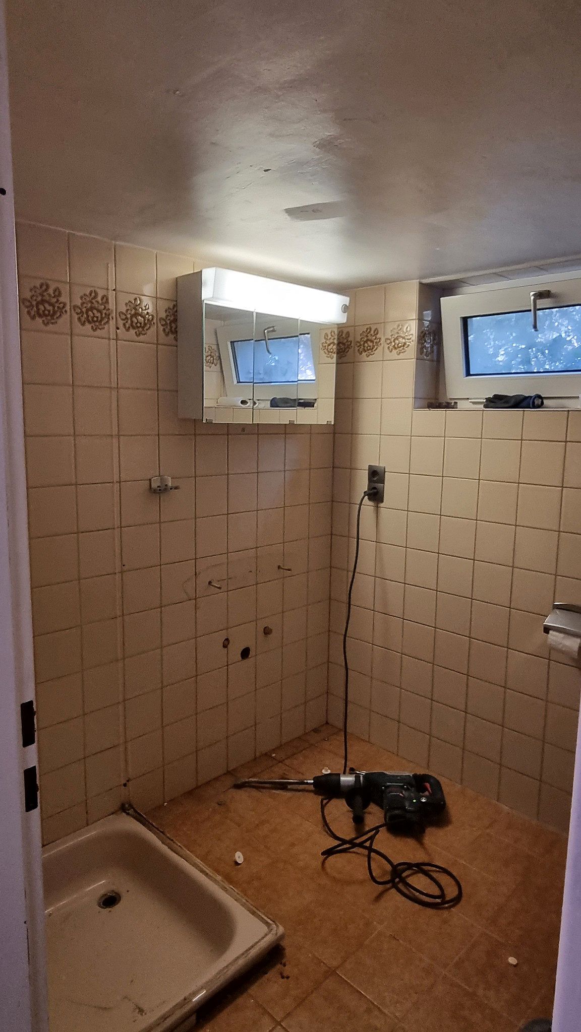 Altes Badezimmer mit beigen Fliesen und Duschtasse vor der Sanierung